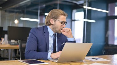 İşadamı dizüstü bilgisayarla çalışırken öksürüyor.