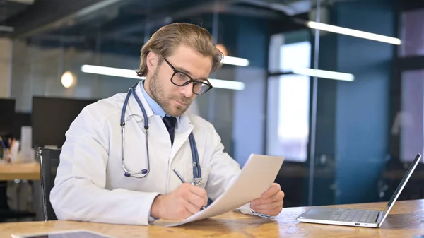 Doctor Reading Medical Documents in Clinic
