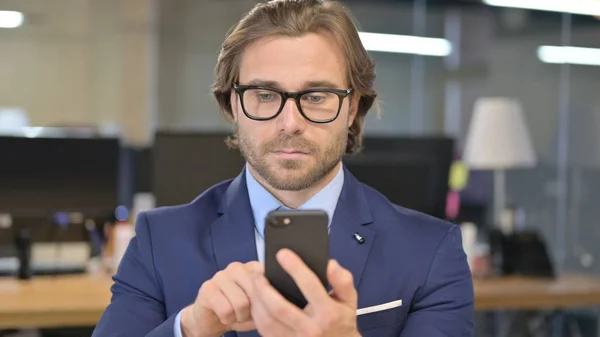 Retrato del hombre de negocios usando smartphone en la oficina — Foto de Stock