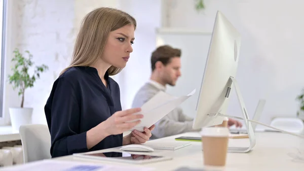 Creative Woman Reading Documents and Working on Desktop