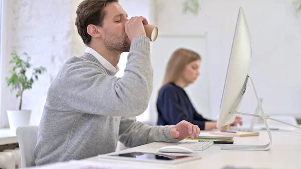 Homem bebendo café e trabalhando na área de trabalho — Fotografia de Stock