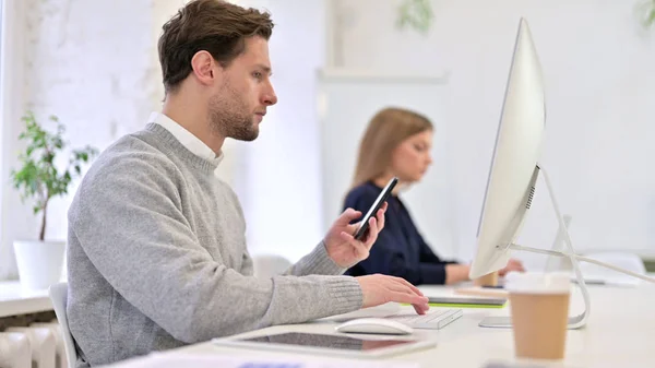 Hombre usando Smartphone y Trabajando en Escritorio — Foto de Stock