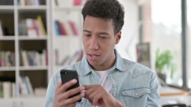 Young African American Man Celebrating Success on Smartphone 