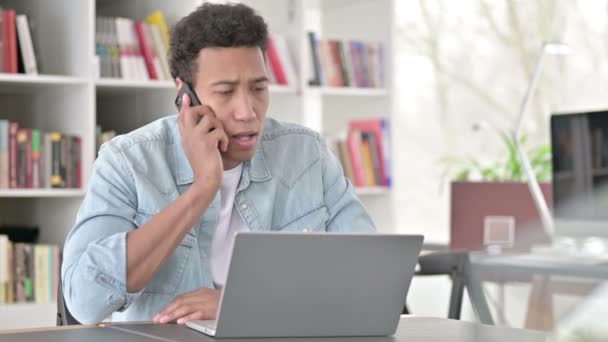Fiatal afro-amerikai férfi beszél okostelefonon a munkahelyen — Stock videók