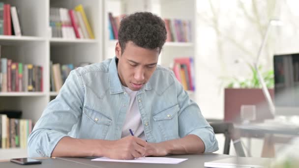 El joven afroamericano estresado no escribe en papel — Vídeos de Stock