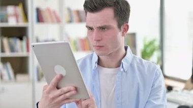 Young Man Upset by Loss on Tablet
