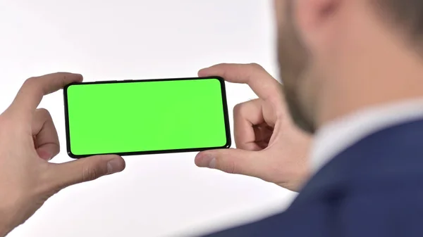 Achteraanzicht van zakenman Video bekijken op mobiele telefoon met chroma scherm, witte achtergrond — Stockfoto