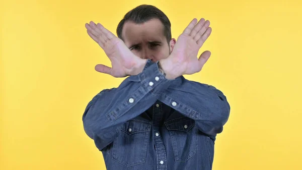 Portrét mladého návrháře mužského pohlaví, který říká ne gestem ruky, žluté pozadí — Stock fotografie