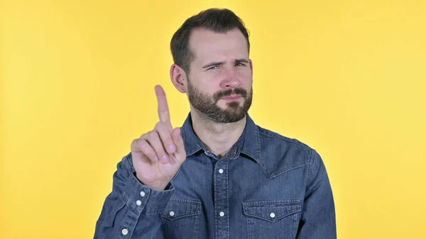 Portret van een jongeman die nee zegt bij vinger, gele achtergrond — Stockfoto