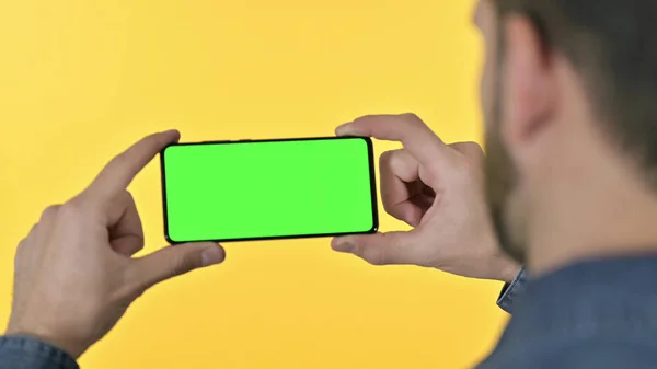Achteraanzicht van de Young Designer Holding Smartphone met Chroma-scherm, Gele achtergrond — Stockfoto