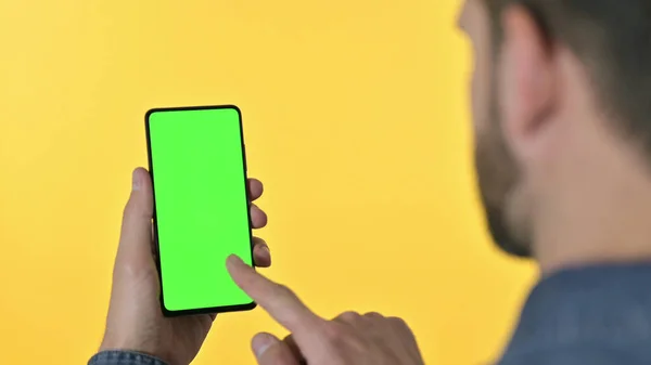Achteraanzicht van Young Designer Scrolling Smartphone met Chroma Screen, Gele achtergrond — Stockfoto