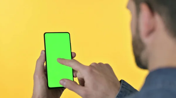 Achteraanzicht van de jonge ontwerper met behulp van Smartphone met chroma scherm, Gele achtergrond — Stockfoto