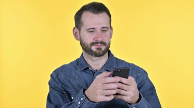 Portrait of Young Man using Smartphone, Yellow Background