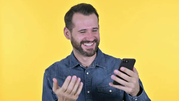 Mann feiert Erfolg auf Smartphone, gelber Hintergrund — Stockfoto