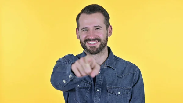 Portret van een jonge man met wijzende vinger naar de camera, gele achtergrond — Stockfoto