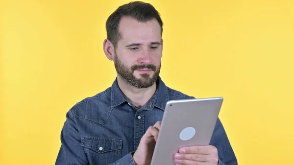 Портрет молодого человека с помощью планшета, желтый фон — стоковое фото