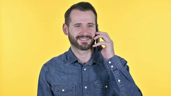 Portret van een jonge man aan het praten op smartphone, gele achtergrond — Stockfoto