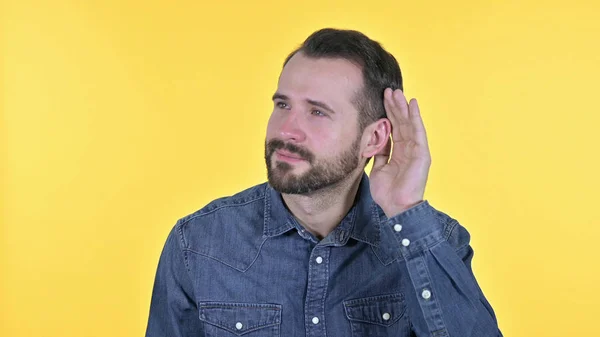 Porträtt av nyfiken ung man lyssna på något, gul bakgrund — Stockfoto