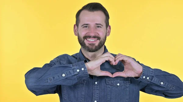Portré a fiatal ember, hogy szív alakja kézzel, sárga háttér — Stock Fotó