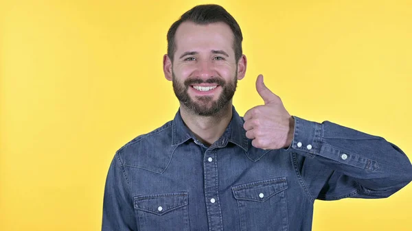Portret van een jonge man met duimen omhoog, gele achtergrond — Stockfoto