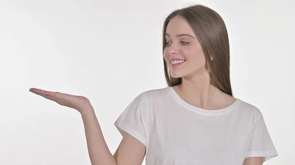 Молода жінка показує продукт на руці, білий фон — стокове фото
