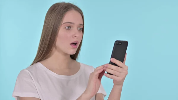 Young Woman Upset by Loss on Smartphone, Blue Background — Stock Photo, Image