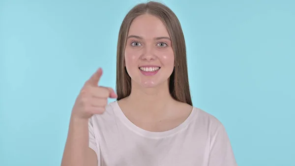 Vacker ung kvinna pekande Finger på kameran, blå bakgrund — Stockfoto