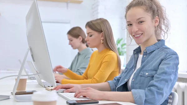 Werkende vrouw met krullende haren glimlachend op camera — Stockfoto