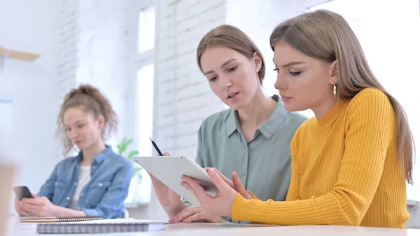 Équipe de jeunes femmes discutant du travail sur tablette — Photo