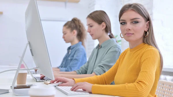 Jeune créatrice travaillant sur le bureau et regardant la caméra — Photo