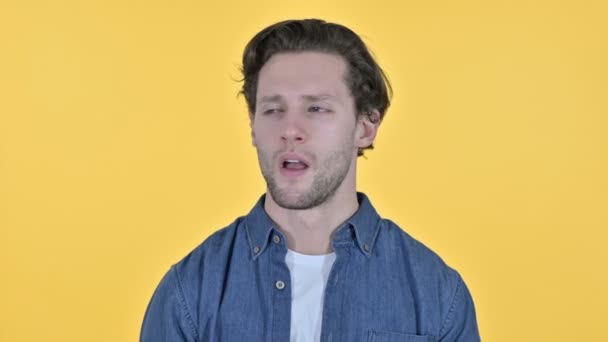 Портрет усталого молодого человека, зевающего на жёлтом фоне — стоковое видео