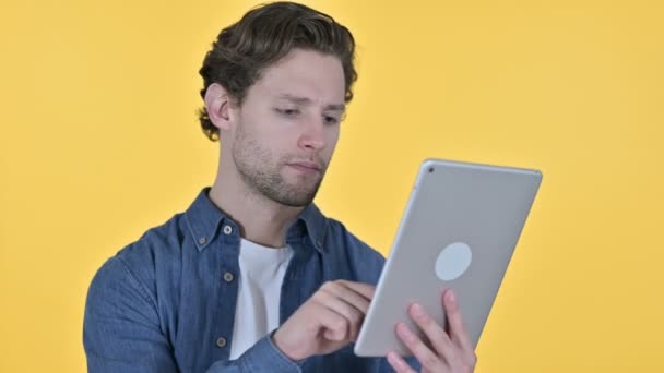 Happy Young Man met behulp van digitale tablet op gele achtergrond — Stockvideo