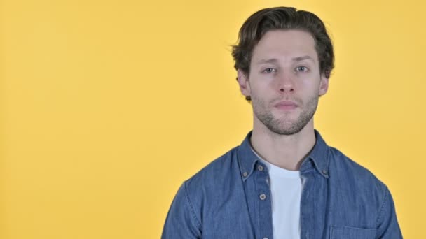 Mladý muž drží ruku ven, Umístění produktu na žlutém pozadí — Stock video