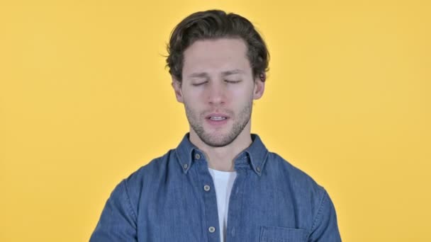 Başı ağrıyan genç adam, sarı arka planda baş ağrısı — Stok video