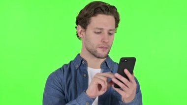 Green Chroma Key 'de akıllı telefon kullanan genç adamın portresi