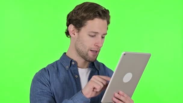 Сосредоточенный молодой человек с помощью цифрового планшета на зеленый ключ хромы — стоковое видео
