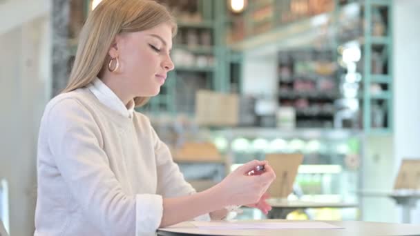 카페 에서 종이에 글을 쓰는 직업적 인 젊은 여자 — 비디오