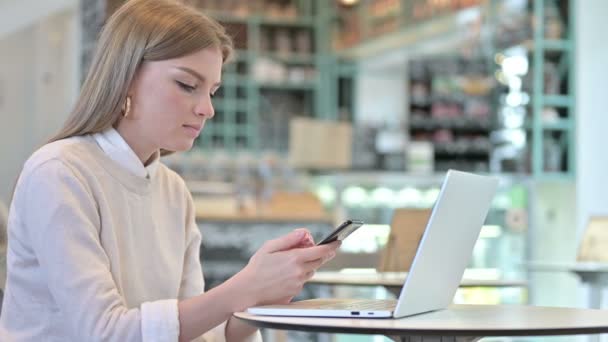Использование смартфона молодой женщиной в кафе — стоковое видео