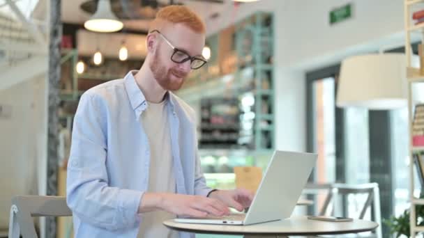 Hüvelykujj fel a vöröshajú férfi laptoppal a Cafe — Stock videók