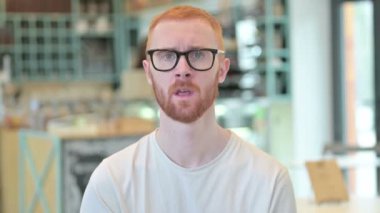 Kameraya bakan üzgün kızıl saçlı adamın portresi.