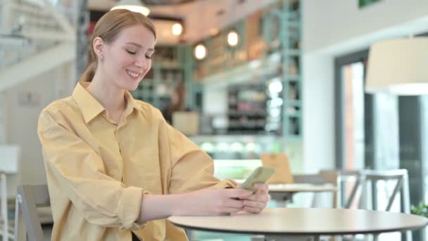 Mujer joven sonriente usando Smartphone en Café — Vídeo de stock