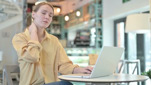 Молодая женщина с болями в шее с помощью ноутбука в кафе — стоковое видео