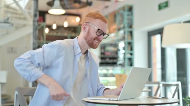 Redhead Man με πόνο στην πλάτη χρησιμοποιώντας Laptop στο Cafe — Αρχείο Βίντεο