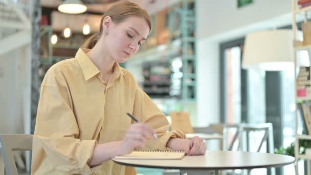Окаменелая молодая женщина занимается бумажной работой в кафе — стоковое видео