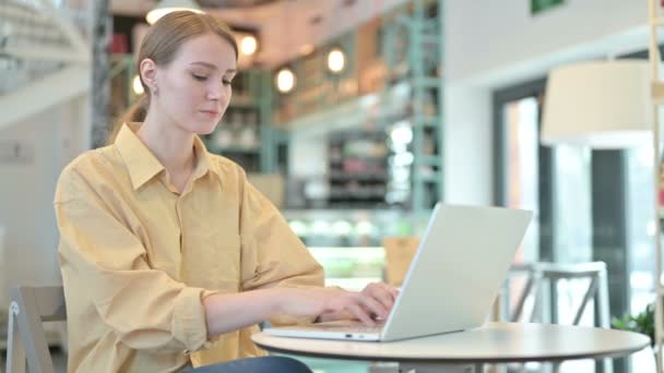 Młoda kobieta świętuje sukces na laptopie w Cafe — Wideo stockowe