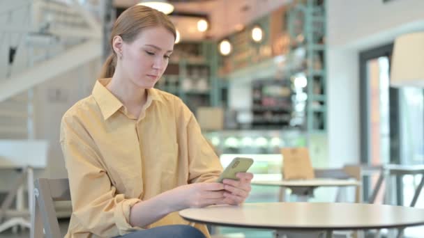 Mujer joven seria usando Smartphone en Café — Vídeos de Stock