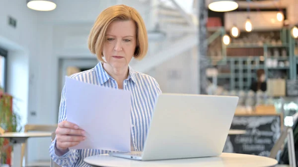 Creativa vecchia donna che lavora su computer portatile e documento in Cafe — Foto Stock