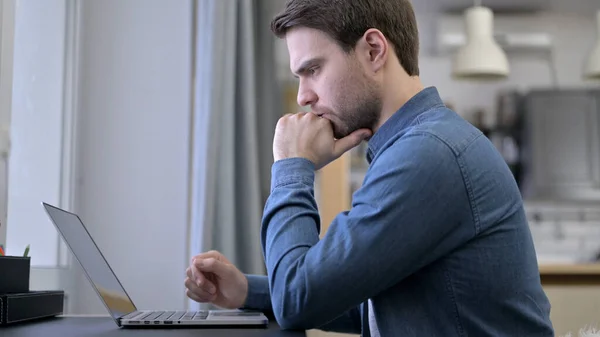Giovane uomo pensare e lavorare sul computer portatile — Foto Stock