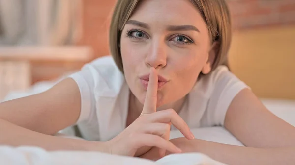 Nahaufnahme einer jungen Frau, die im Bett Finger auf Lippen legt — Stockfoto