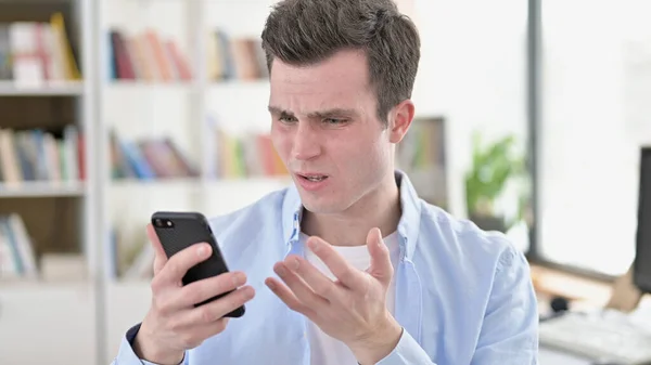 당황 한 젊은 남자가 스마트폰으로 충격을 받다 — 스톡 사진